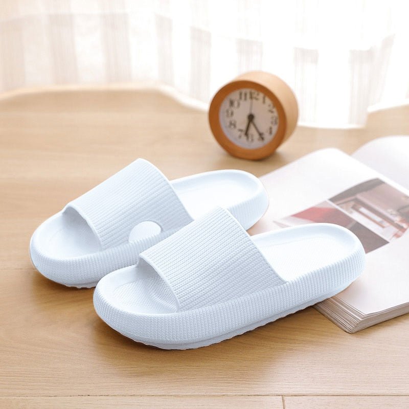 Weiße Pantoletten aus Kunststoff auf Holzboden, bequem, modern, ideal für den Sommer.