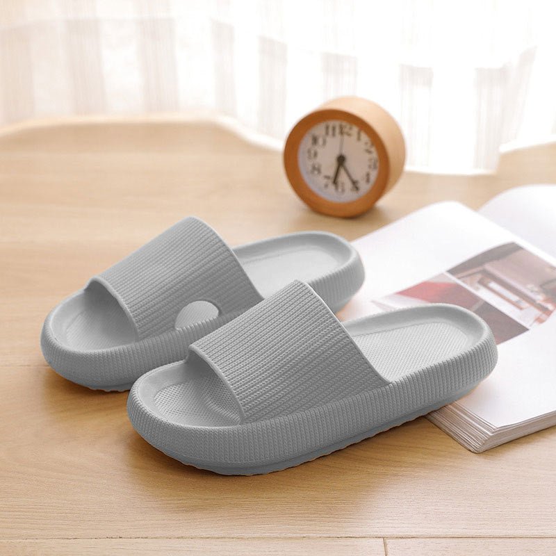 Graue Pantoletten aus Kunststoff auf Holzboden, bequemes Design, ideal für den Sommer.