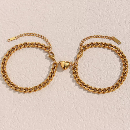 Zwei goldene Armbänder mit Herzverschluss auf weißem Hintergrund, modischer Schmuck.