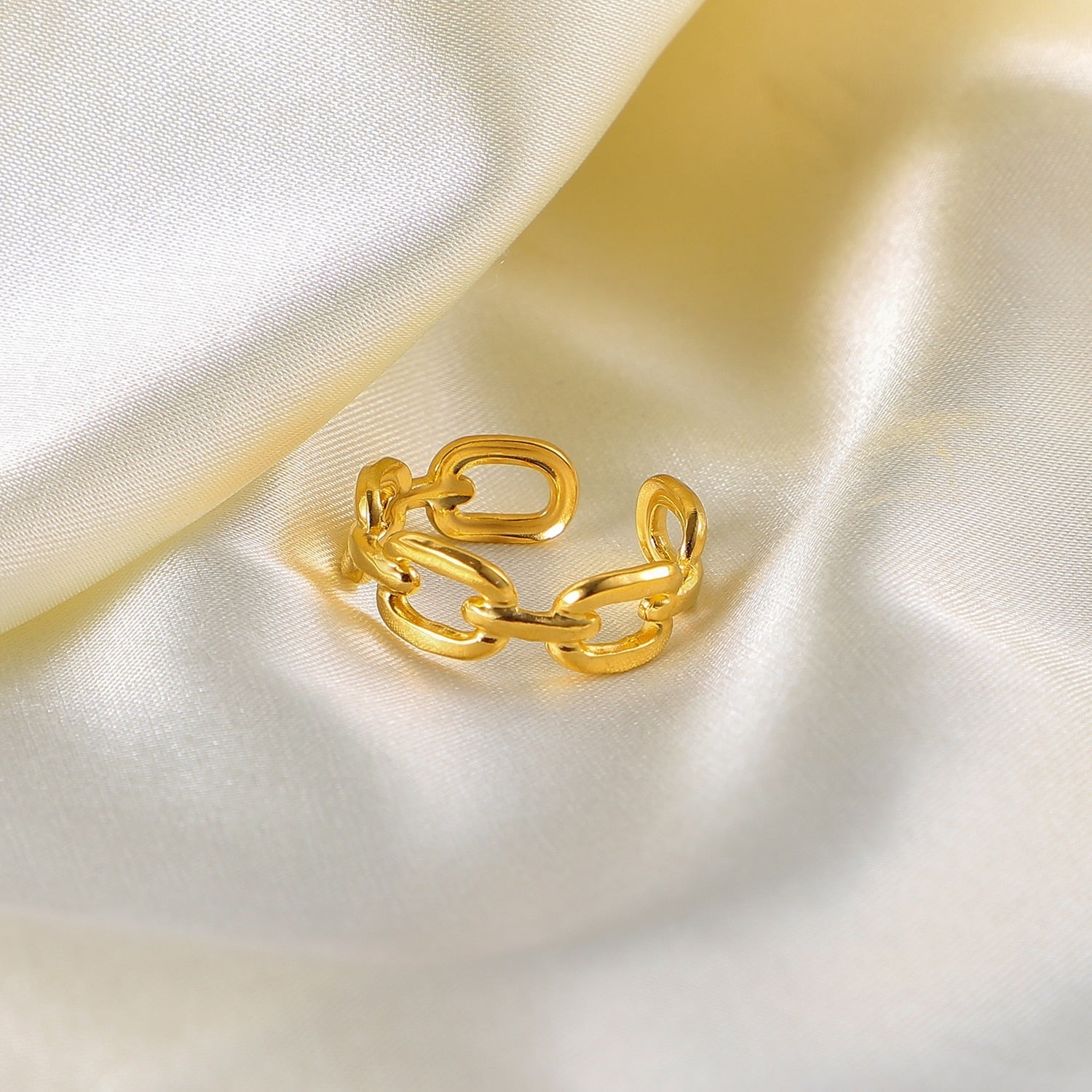 Goldener Kettenring auf weißem Satin, verstellbar, modisches Schmuckstück, elegantes Design.