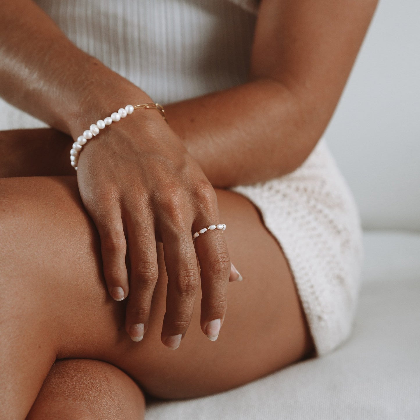 Frau mit Perlenring und Armband, Gold, Schmuck, Mode, elegantes Design, Nahaufnahme.