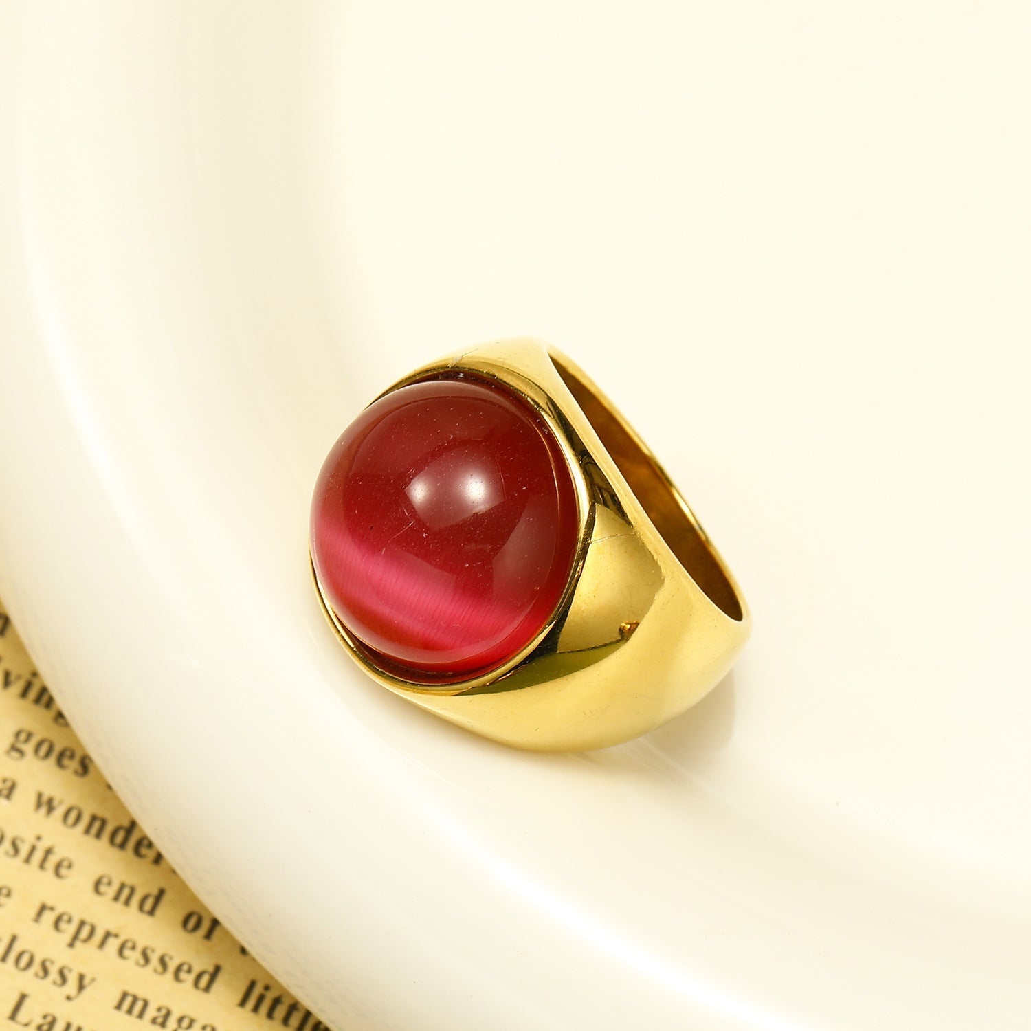 Goldener Ring mit rotem Katzenauge-Stein, eleganter Schmuck, modisches Accessoire.