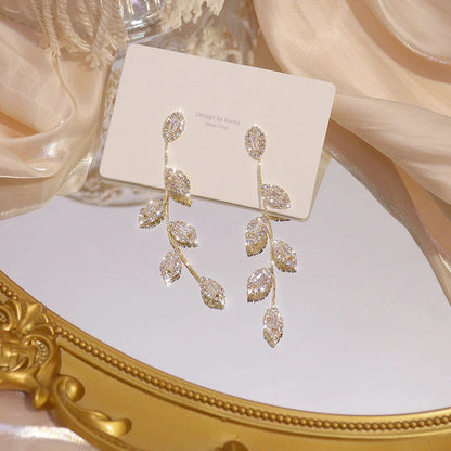 Goldene Ohrringe mit Blattdesign, funkelnde Kristalle, eleganter Schmuck, Damenaccessoire.