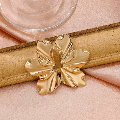 Goldene, blattförmige Ohrringe auf rosa Stoff, eleganter Schmuck, modisches Accessoire.