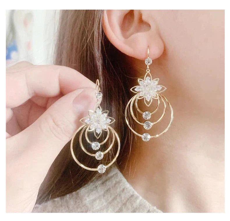 Goldene Ohrringe mit Blumenmotiv und Kristallen, eleganter Schmuck für Damen.