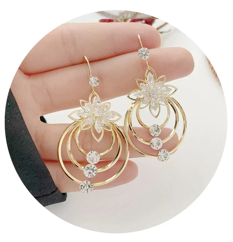 Goldene Ohrringe mit Blumenmotiv und Kristallen, eleganter Schmuck für Damen, modisch und stilvoll.