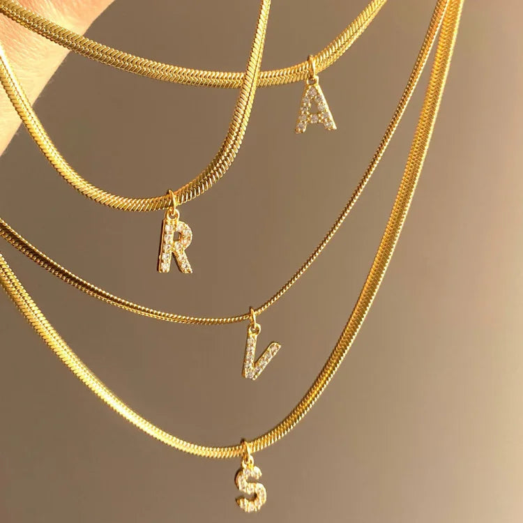 Goldene Halsketten mit Buchstabenanhängern R, A, V, S, glänzend, modisch, Schmuckaccessoire.