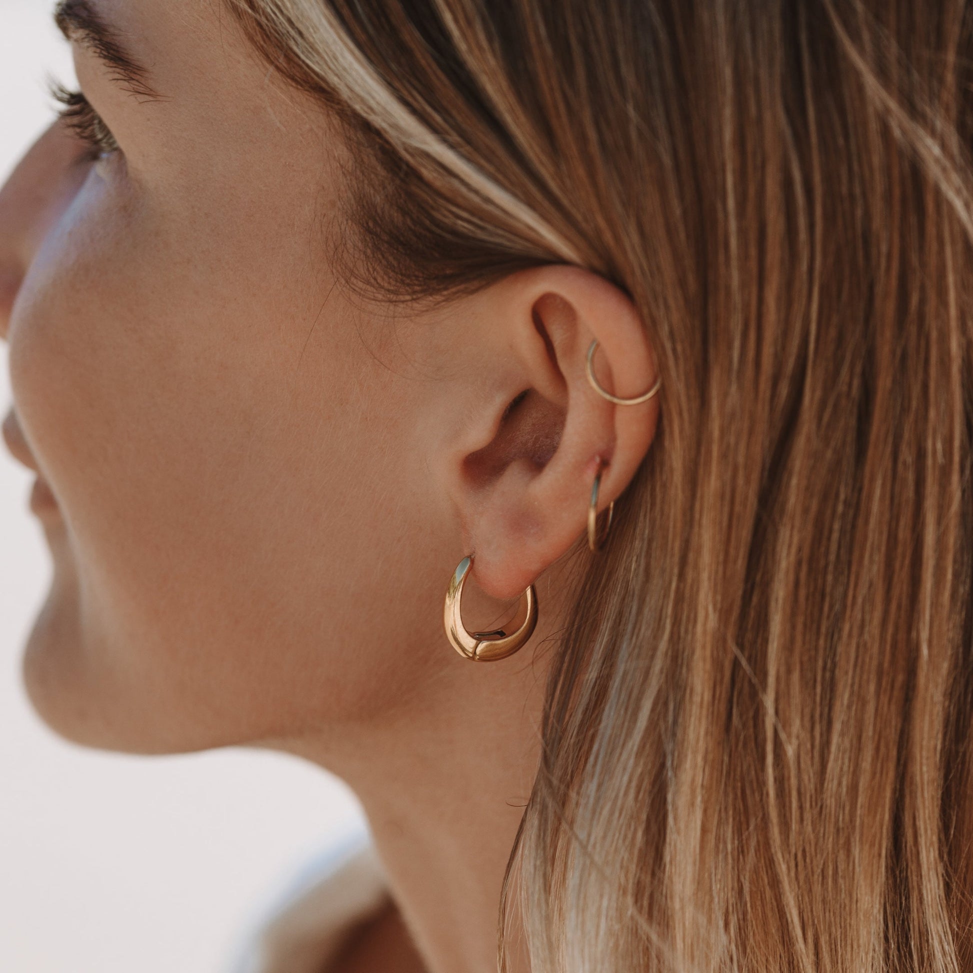 Frau mit goldenen Creolen-Ohrringen, Nahaufnahme, modischer Schmuck, elegantes Design.