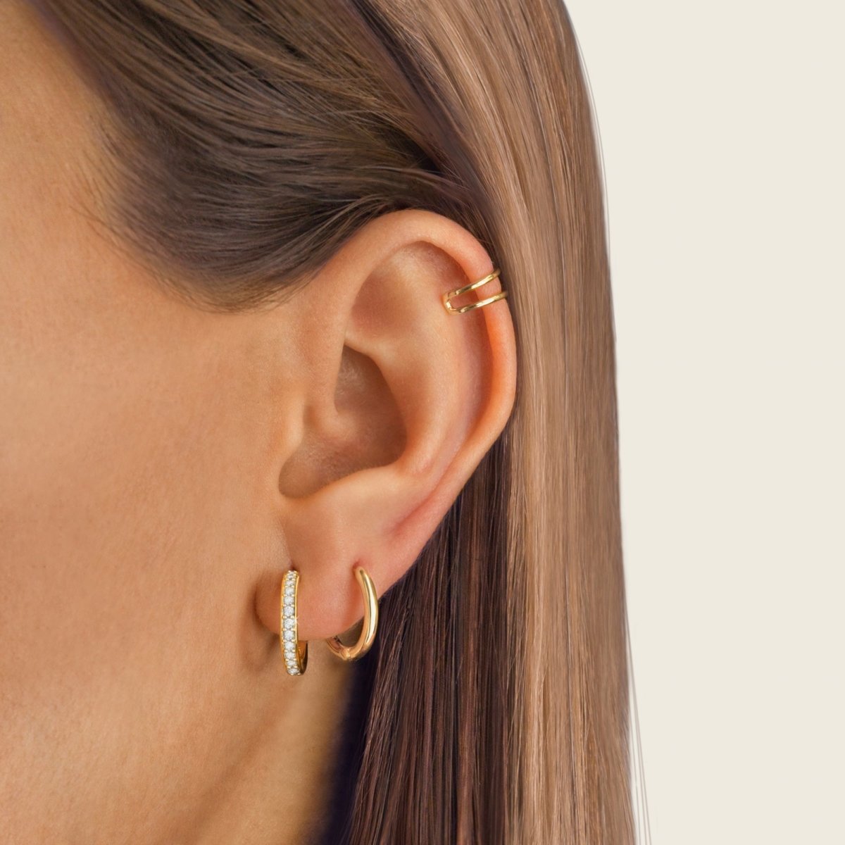 Frau mit goldenen Creolen und Ohrklemme, Schmuck, elegantes Design, Nahaufnahme.