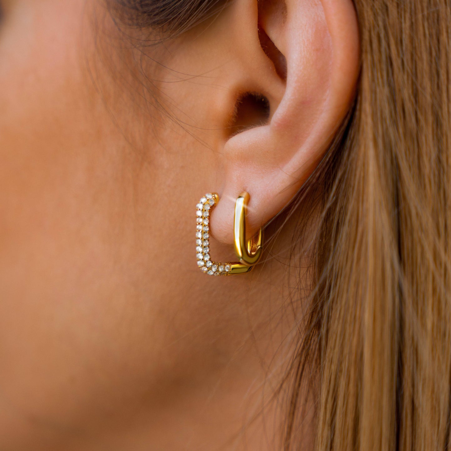 Goldene Creolen Ohrringe mit Strasssteinen, eleganter Schmuck für Damen, Nahaufnahme.