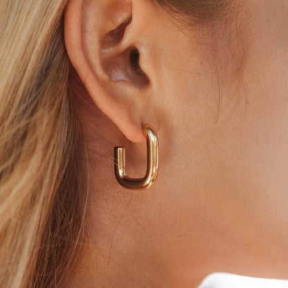 Goldene Creolen-Ohrringe, glänzend, modern, an Ohr getragen, Schmuck für Damen.