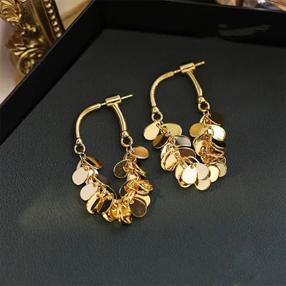 Goldene Creolen Ohrringe mit runden Anhängern, modisches Schmuckdesign, elegant und glänzend.