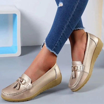 Goldene Damen-Mokassins mit Quasten, Leder, bequeme Freizeitschuhe, blaue Jeans.