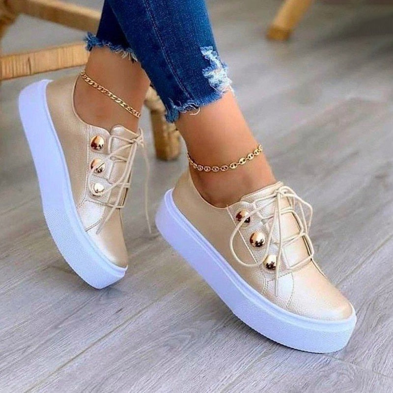 Goldene Damen-Sneaker mit Plateau, Schnürsenkeln und Jeans, modische Freizeitschuhe.