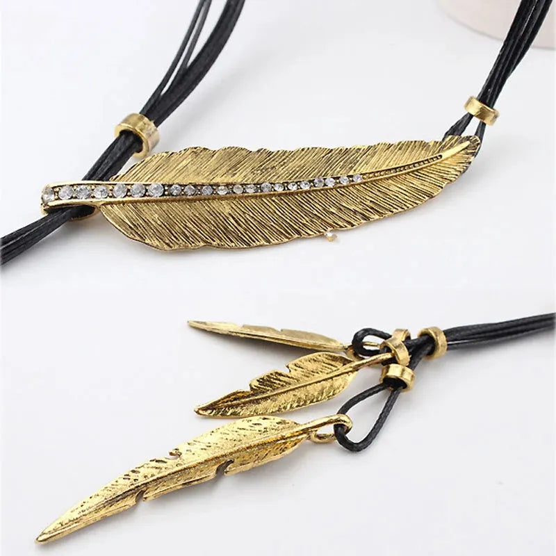 Goldene Feder-Halskette mit Strasssteinen, schwarzes Lederband, modisches Schmuckdesign.