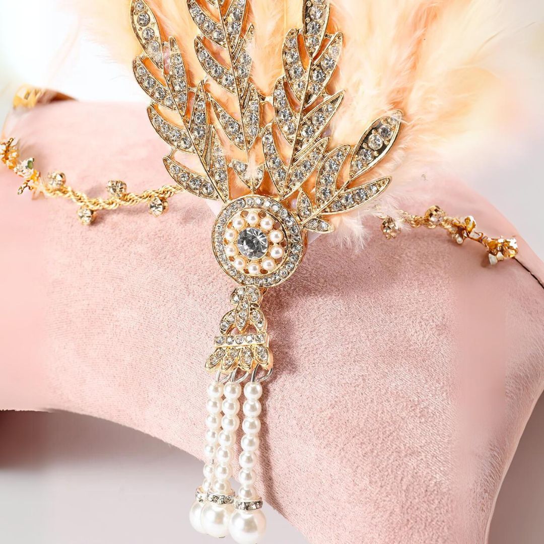 Goldene Strass-Haarspange mit Perlen und Federn auf rosa Hintergrund, eleganter Haarschmuck.