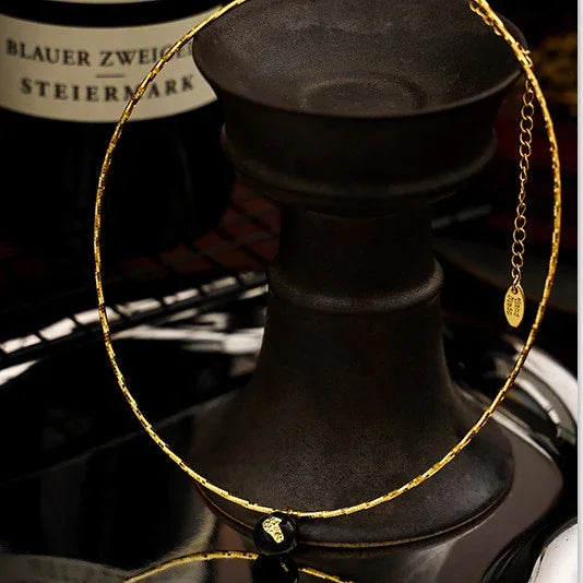 Goldene Halskette mit schwarzem Anhänger, elegantes Schmuckdesign, luxuriöses Accessoire.