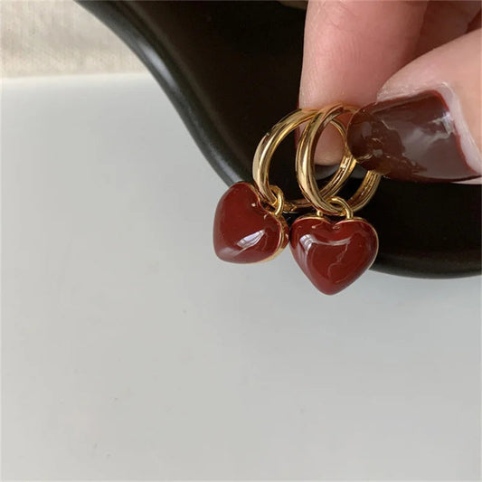Goldene Ohrringe mit roten Herzanhängern, eleganter Schmuck, modisches Accessoire.