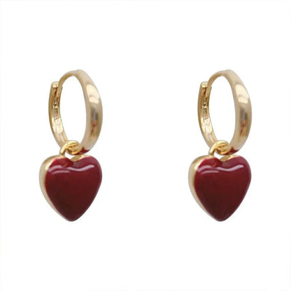 Goldene Ohrringe mit roten Herzanhängern, modischer Schmuck, elegantes Design.