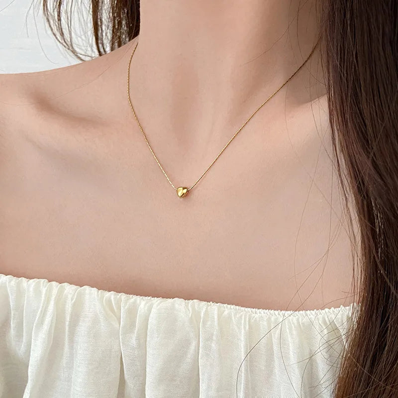 Frau mit goldener Herz-Halskette, elegantes Schmuckstück, minimalistisch, modisch, Geschenkidee.