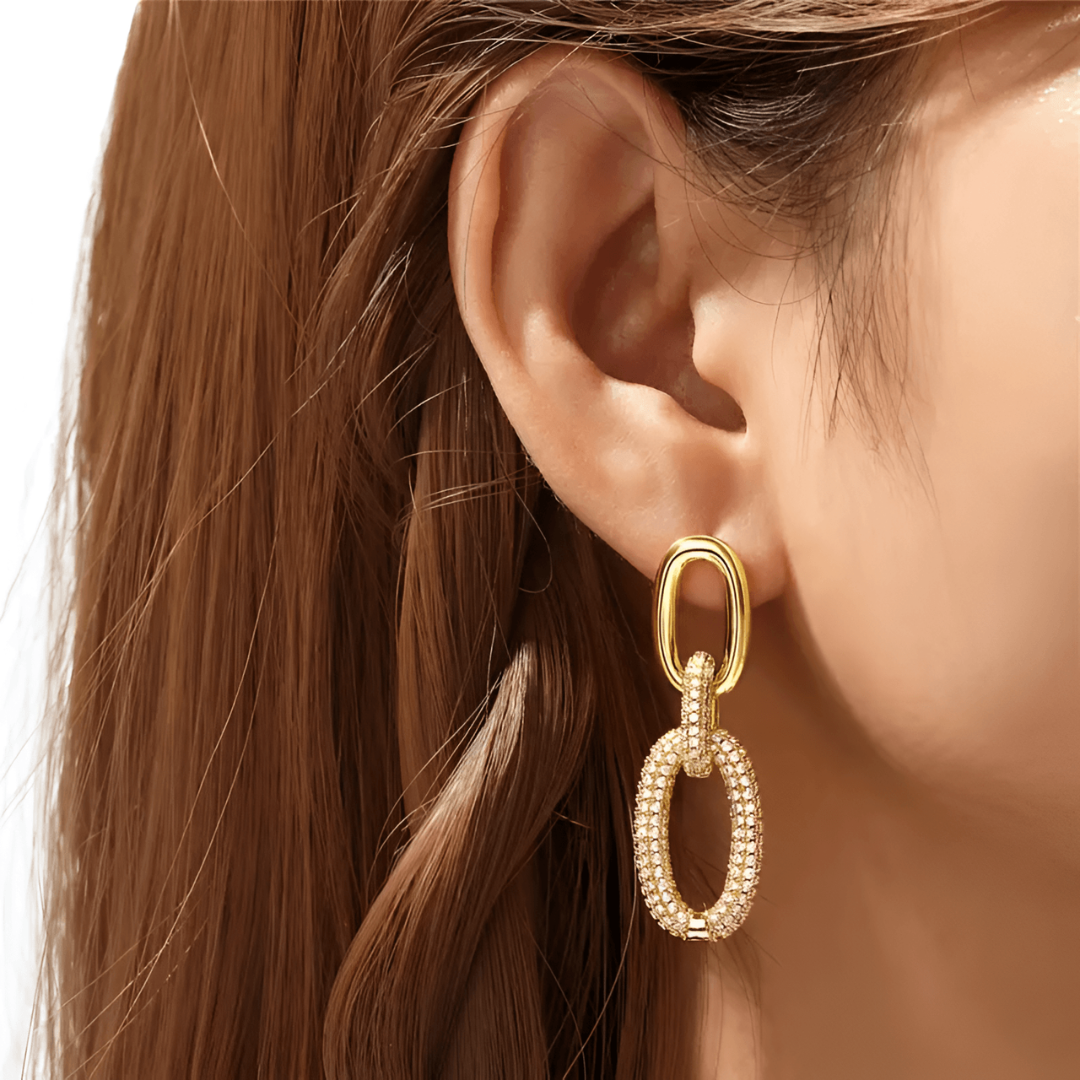 Goldene Ohrringe an Frauenohr, elegantes Schmuckdesign, modische Accessoires, Nahaufnahme.