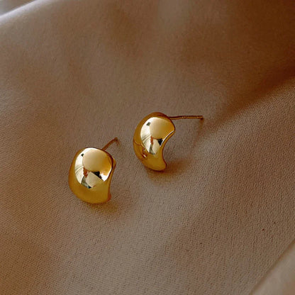 Goldene Ohrringe auf beigem Stoff, elegantes Design, Schmuck, Accessoires, Mode.