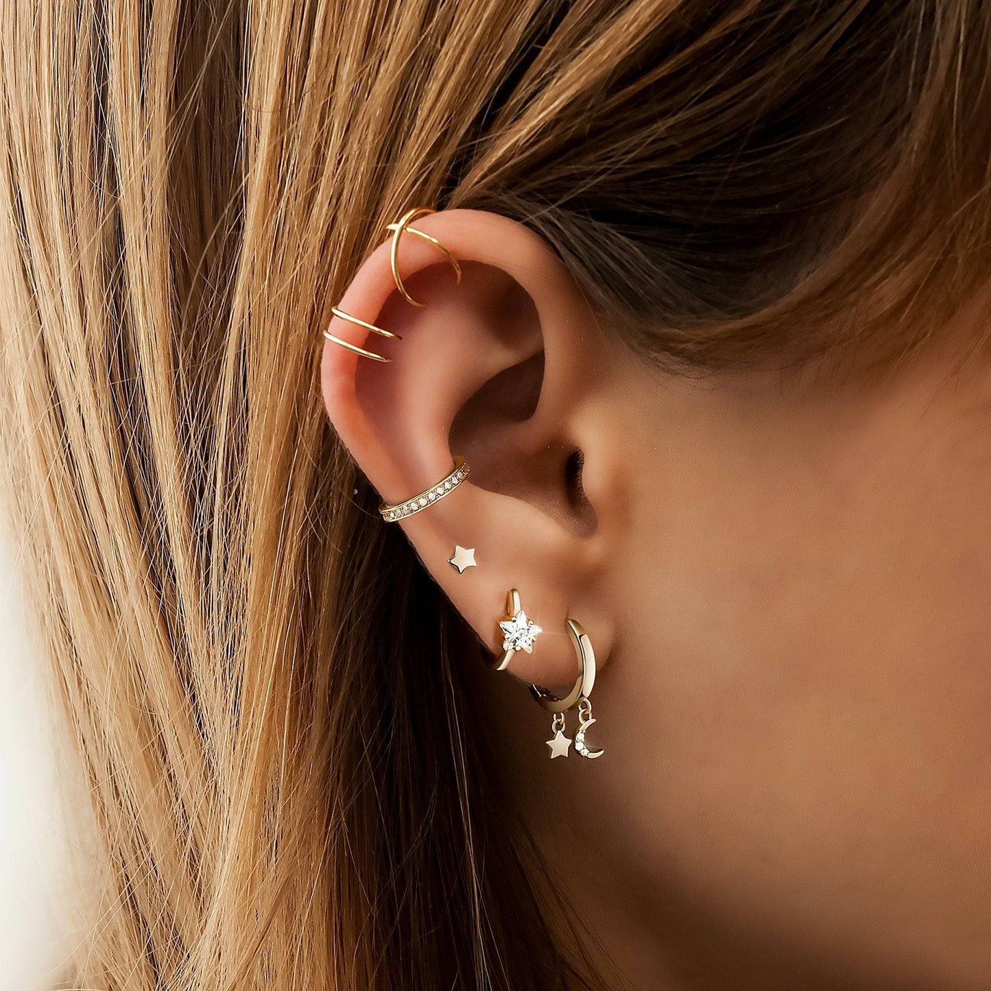 Frau mit goldenen Ohrringen, Stern- und Mondanhänger, modischer Schmuck, Nahaufnahme.