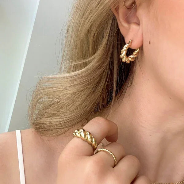 Frau mit goldenen Creolen und Ring, Schmuck, Modeaccessoires, elegantes Design, Nahaufnahme.