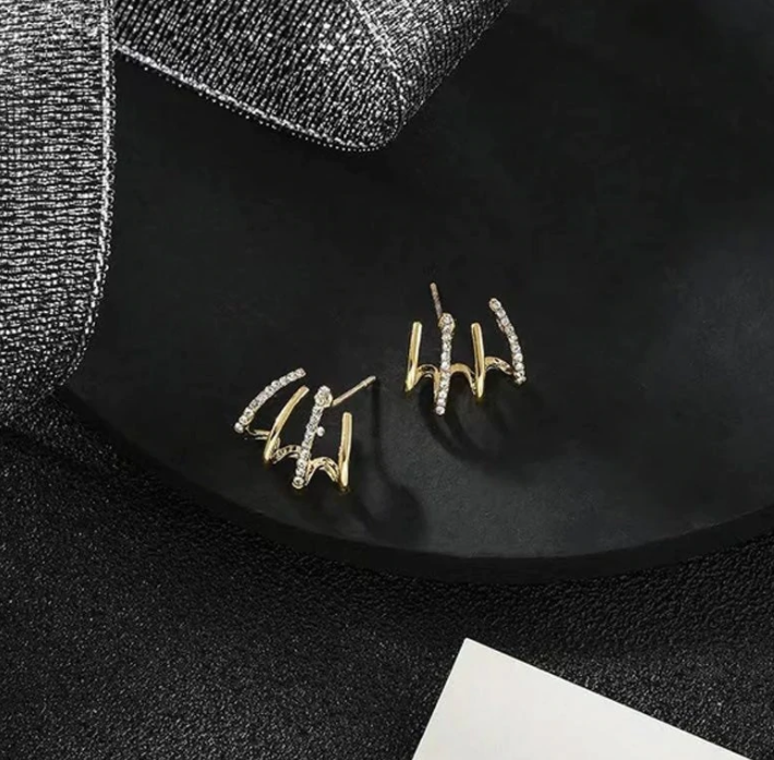 Goldene Ohrringe mit Diamanten auf schwarzem Hintergrund, eleganter Schmuck, Geschenkidee.