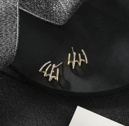 Goldene Ohrringe mit Diamanten auf schwarzem Hintergrund, eleganter Schmuck, Geschenkidee.