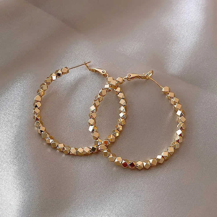 Goldene Creolen Ohrringe, facettierte Perlen, modischer Schmuck, elegantes Design, Damenaccessoire.