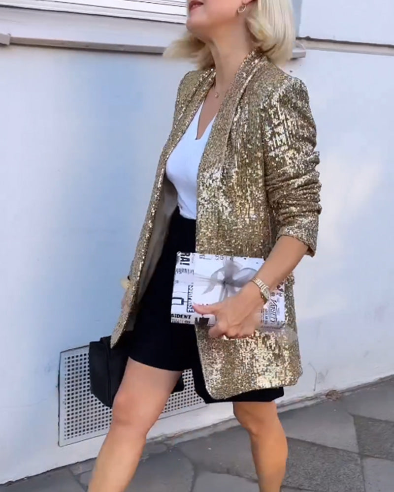 Frau in goldener Paillettenjacke, weißem T-Shirt, schwarzem Rock, hält Zeitungstasche.