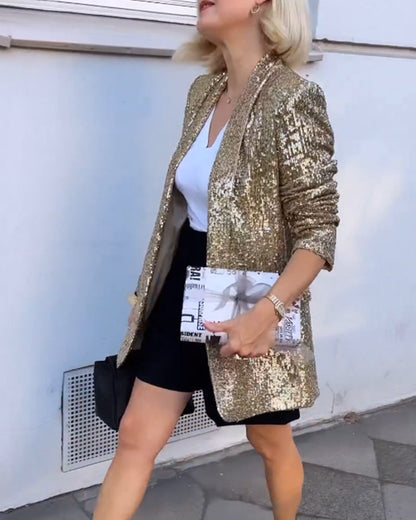 Frau in goldener Paillettenjacke, weißem T-Shirt, schwarzem Rock, hält Zeitungstasche.
