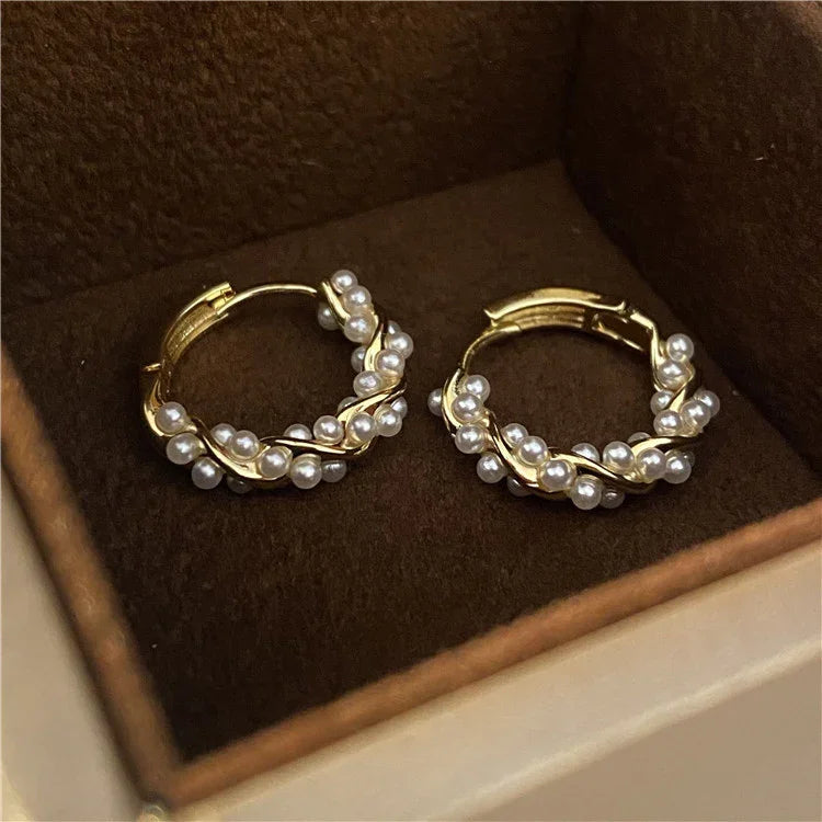 Goldene Creolen mit Perlen, eleganter Schmuck, luxuriöses Design, in brauner Schmuckschatulle.