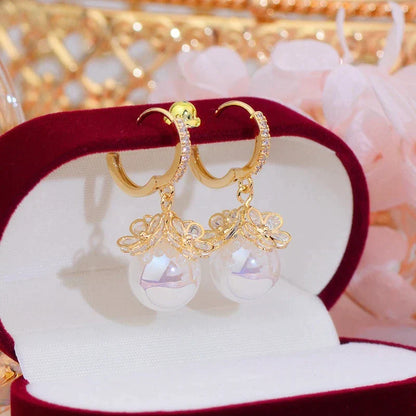 Goldene Ohrringe mit Perlen, Schmuckkästchen, elegantes Design, Damenaccessoire.