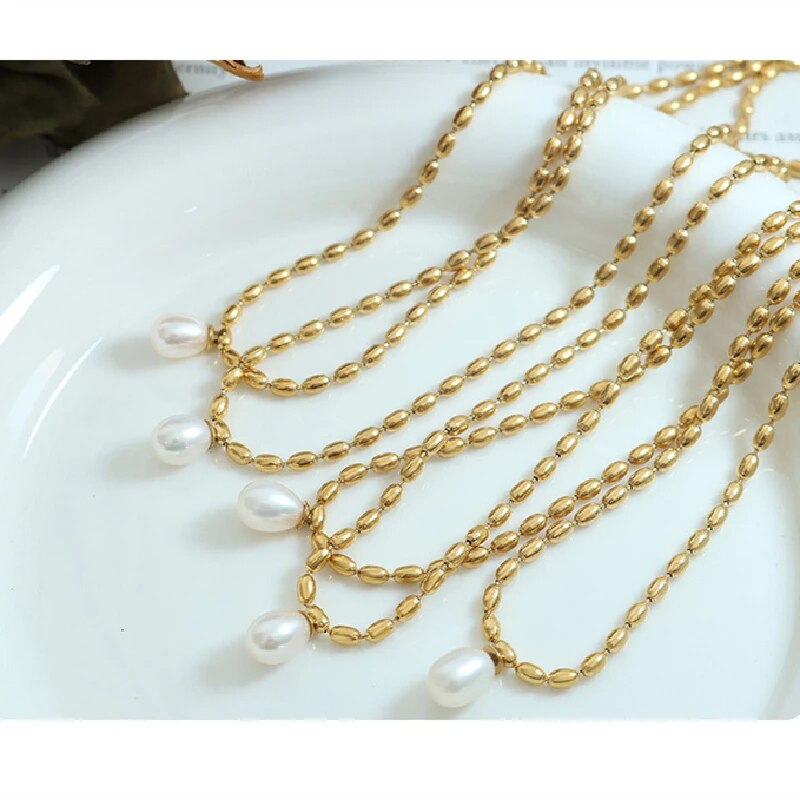 Goldene Halskette mit Perlenanhänger, eleganter Schmuck, Damenaccessoire, modisch, luxuriös.