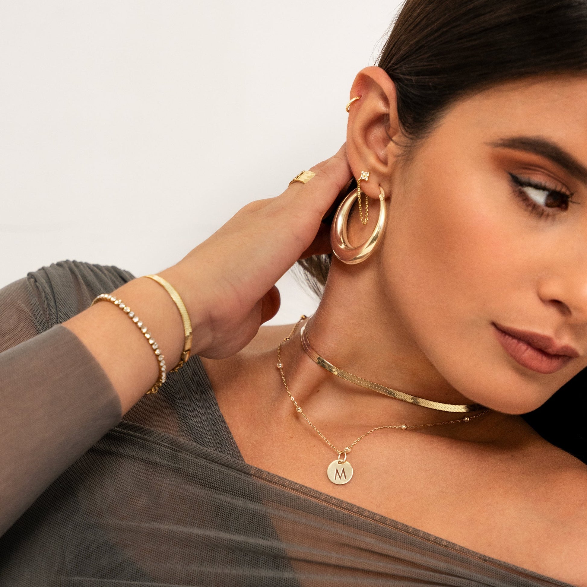 Frau mit goldenen Ohrringen, Halsketten und Armbändern, Schmuckmode, eleganter Stil.
