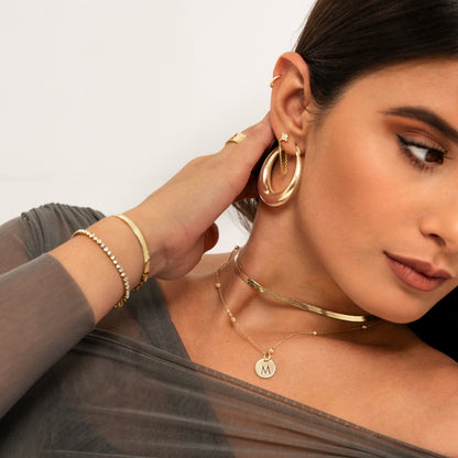 Frau mit goldenen Ohrringen, Halsketten und Armbändern, Schmuckmode, eleganter Stil.