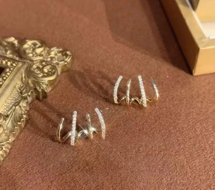 Goldene Ohrringe mit Diamanten, elegantes Design, Schmuck auf braunem Hintergrund.