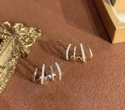 Goldene Ohrringe mit Diamanten, elegantes Design, Schmuck auf braunem Hintergrund.