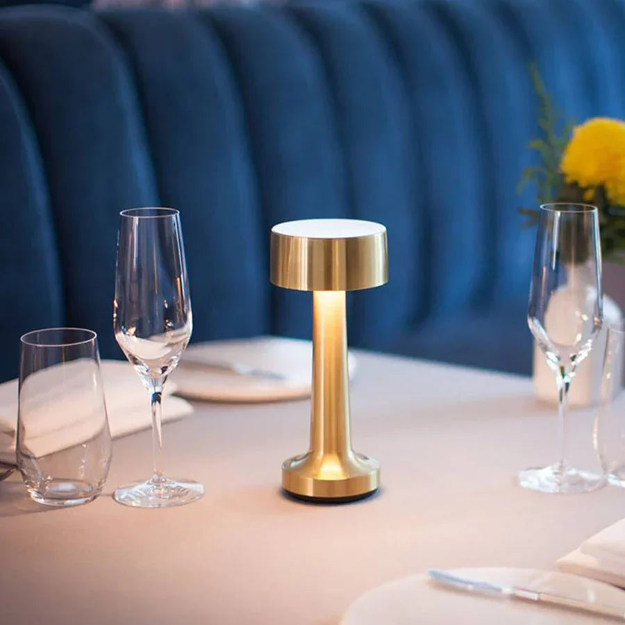 Goldene LED-Tischlampe auf gedecktem Tisch, modernes Design, ideal für Esszimmerbeleuchtung.