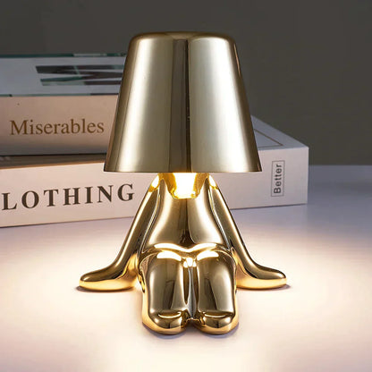 Goldene Tischlampe in Form einer sitzenden Figur, modernes Design, ideal für Wohnzimmer-Dekor.