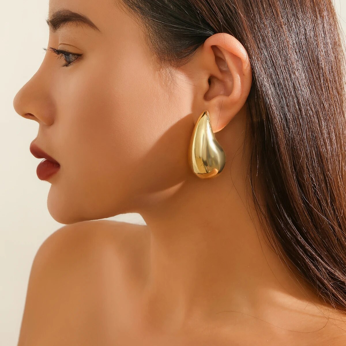 Frau mit großen goldenen Ohrringen, eleganter Schmuck, modisches Accessoire, Nahaufnahme.