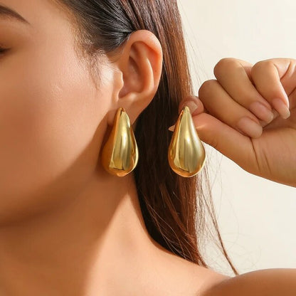 Frau mit großen goldenen Tropfen-Ohrringen, eleganter Schmuck, Nahaufnahme.