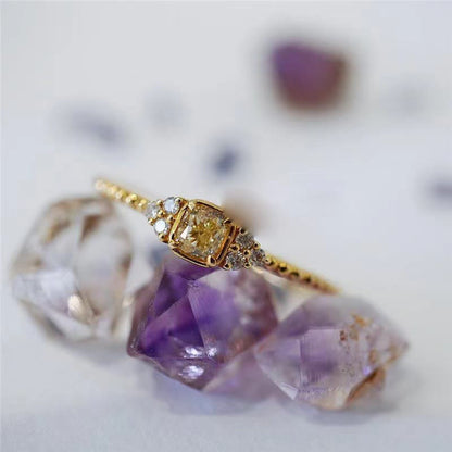 Goldener Diamantring mit gelbem Stein, umgeben von Amethysten, elegantes Schmuckdesign.