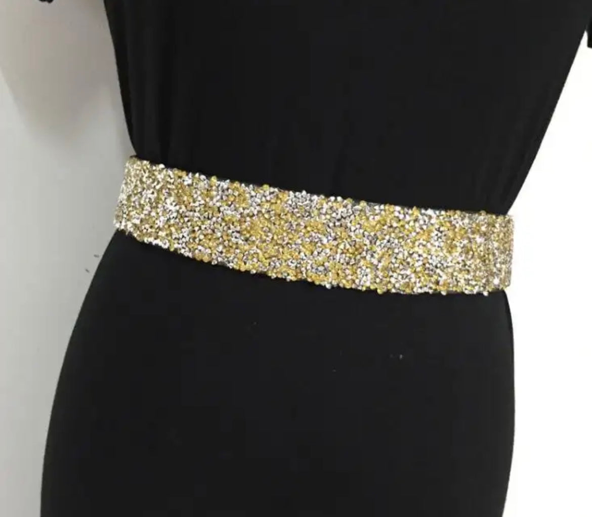 Goldener Pailletten-Gürtel auf schwarzem Kleid, modisches Accessoire, glänzend, elegant.