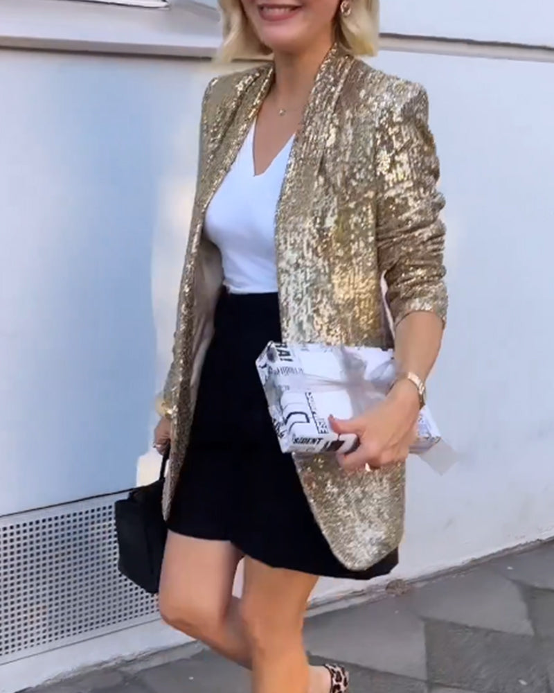 Frau in goldenem Paillettenblazer, weißem Top, schwarzem Rock, hält Geschenk, modisch, elegant.