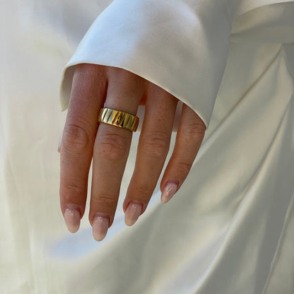 Goldener Ring an Hand mit weißem Seidenhemd, elegantes Schmuckdesign, Damenmode Accessoire.