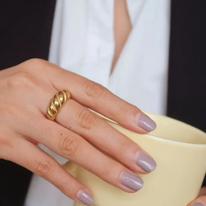 Goldener Ring an Hand, gedrehte Optik, elegantes Design, Damenmode, Schmuckaccessoire.