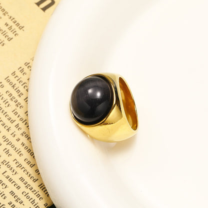 Goldener Ring mit schwarzem Stein auf weißem Teller, elegantes Schmuckdesign.